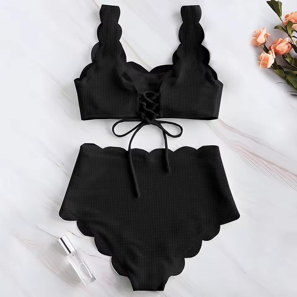 Black textured bikini with scalloped edges and tie-front top on white marble background