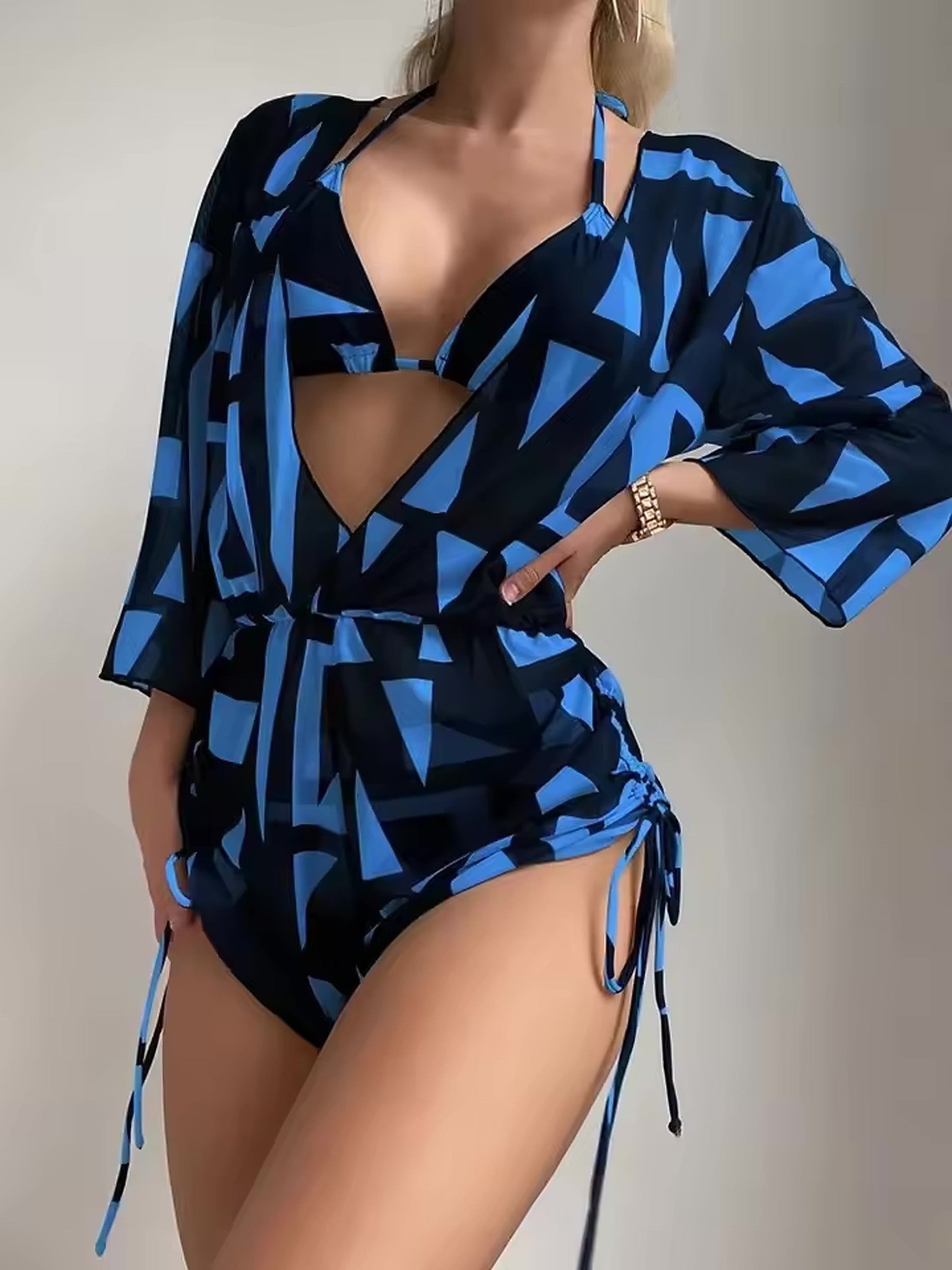 Woman wearing blue and black geometric print bikini with matching cover-up shirt and adjustable side ties.