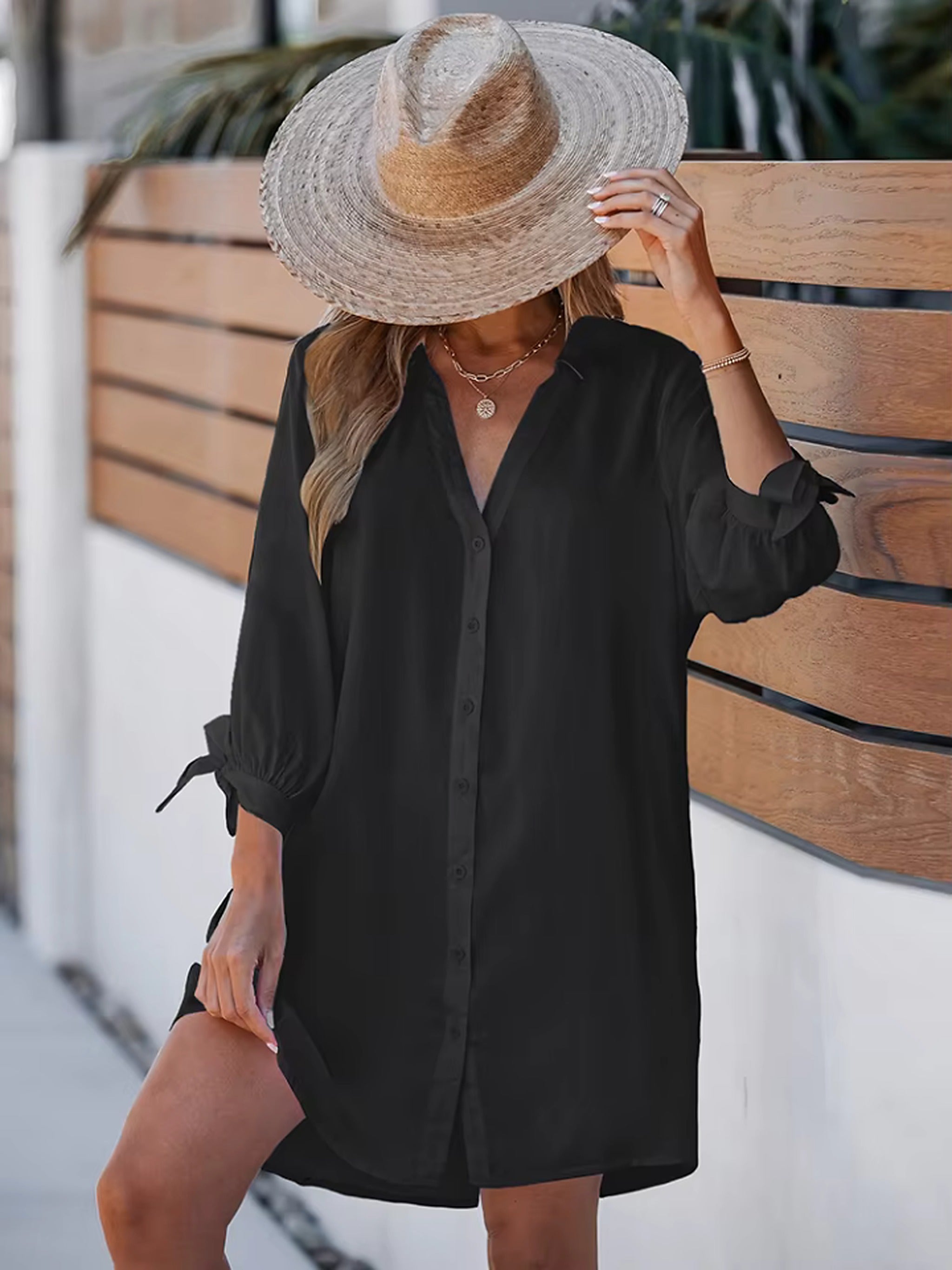Woman wearing black button-up beach cover-up shirt over striped catch bikini with wide-brimmed straw hat