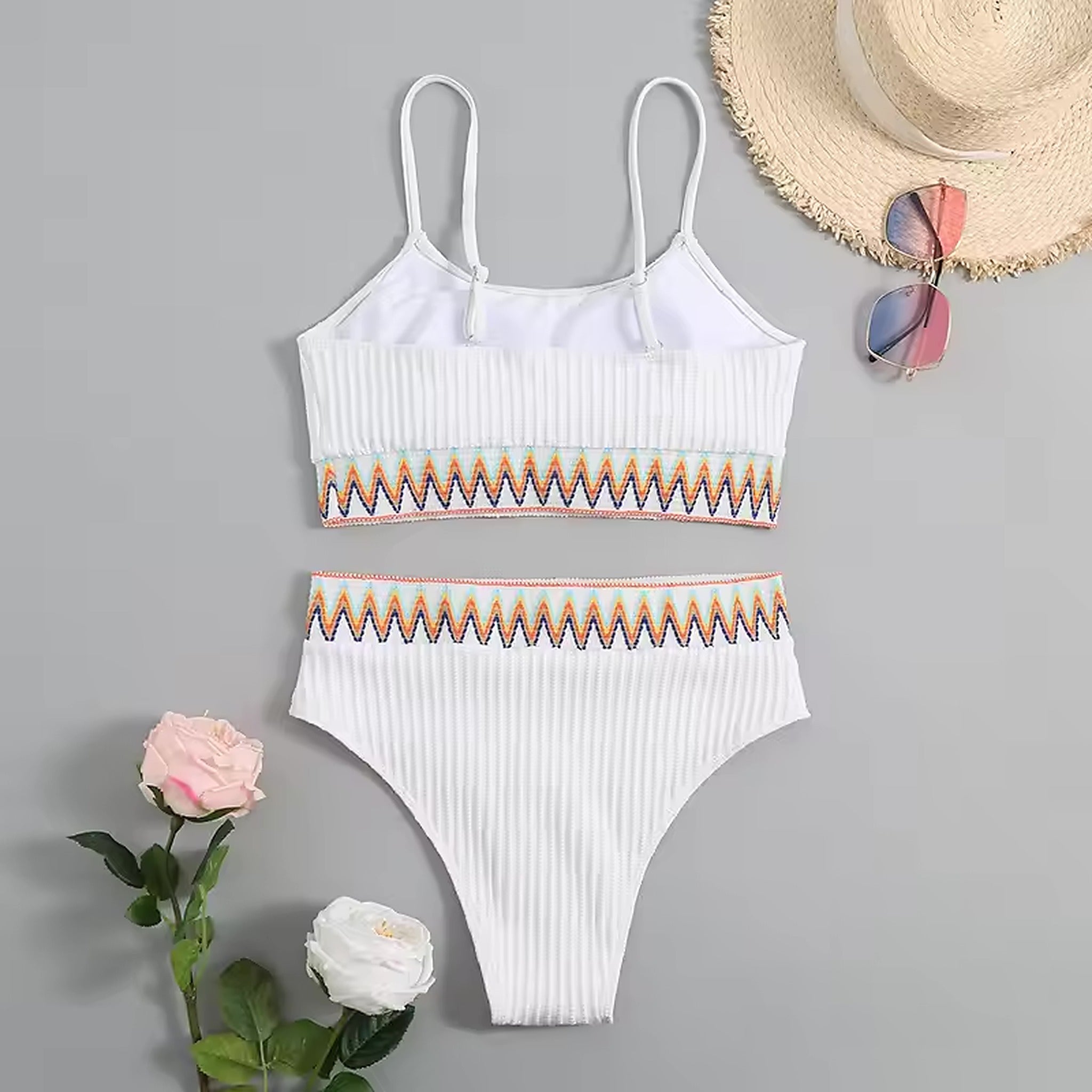 White ribbed bikini with colorful geometric trim and adjustable straps, displayed with straw hat and sunglasses