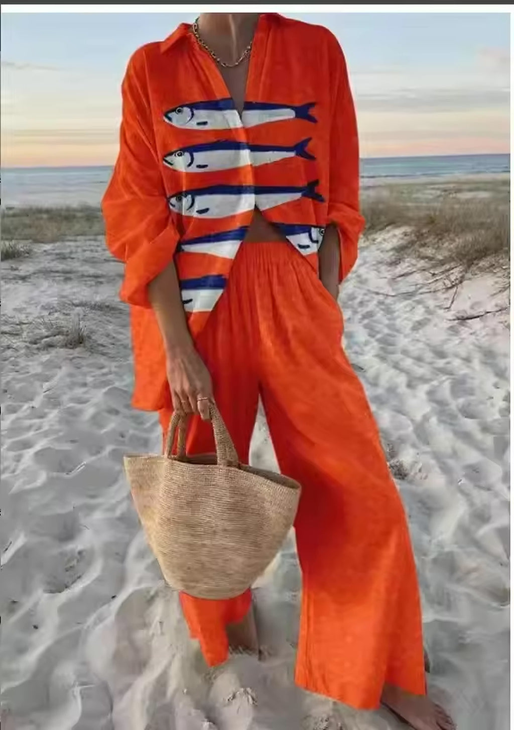 Woman wearing red Sahara Pop bikini with fish print design on sandy beach at sunset