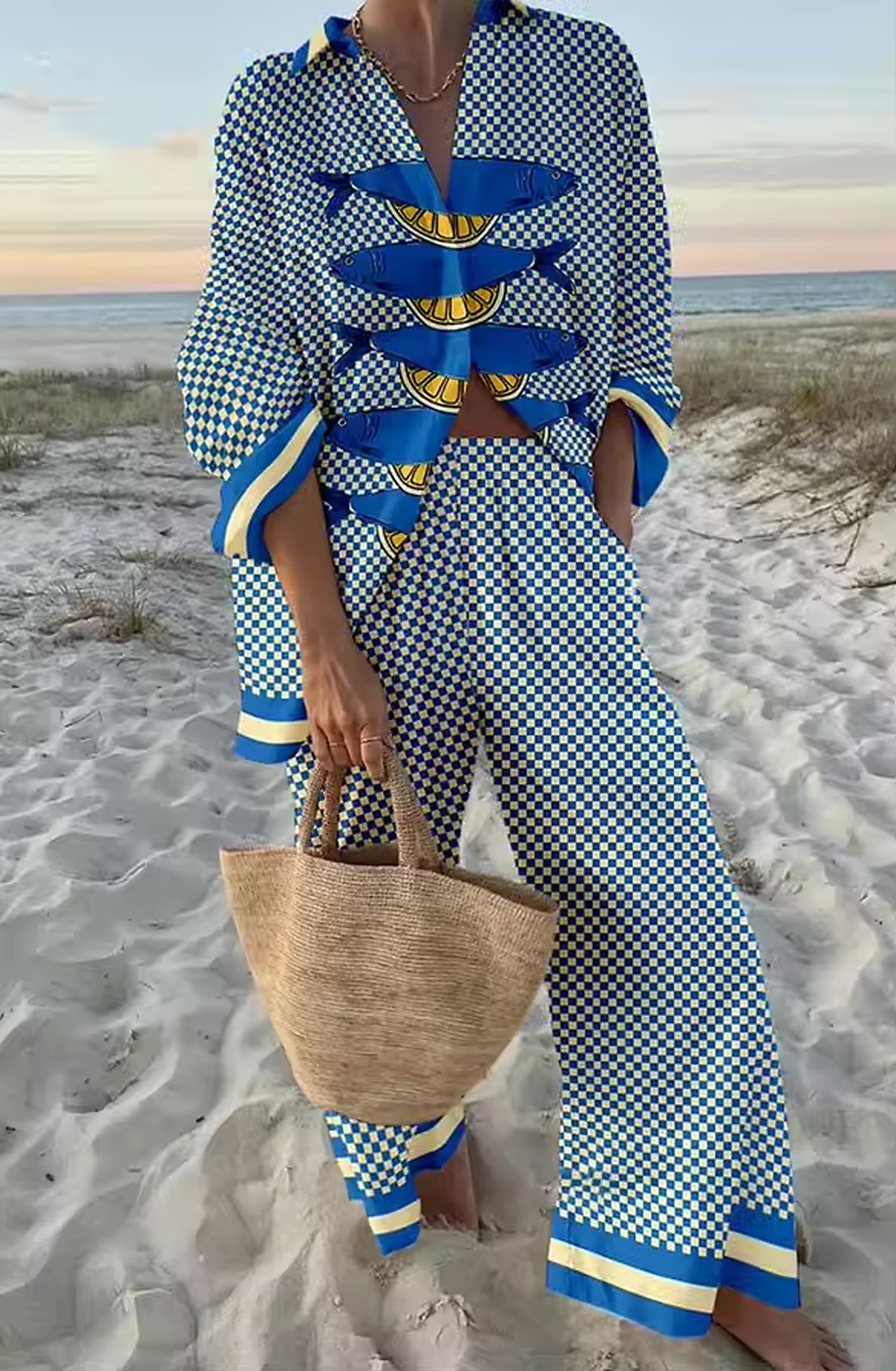 Woman wearing blue and white checkered bikini with banana print details on beach at sunset