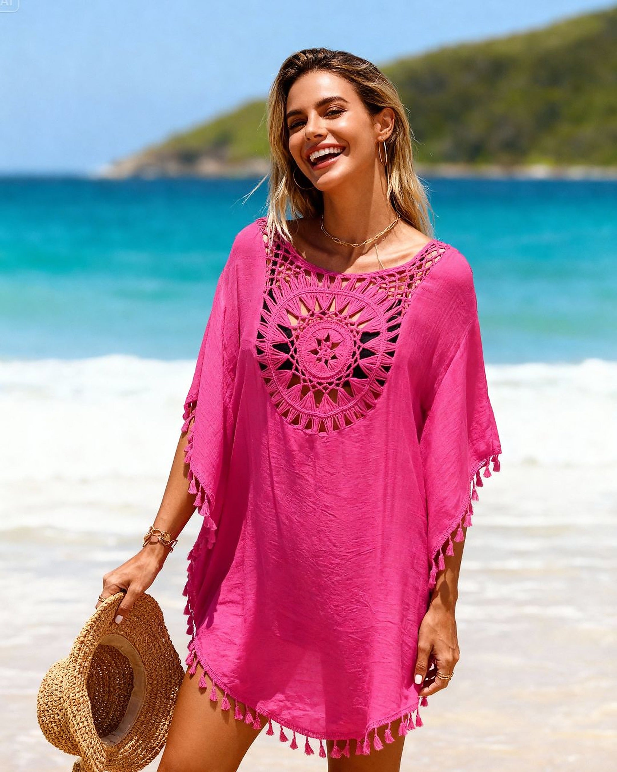 Bright pink crochet beach dress with tassel trim worn on sunny shoreline
