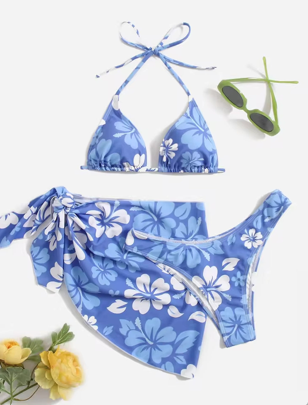 Blue floral bikini set with halter top and matching sarong wrap, styled with sunglasses and yellow flowers.