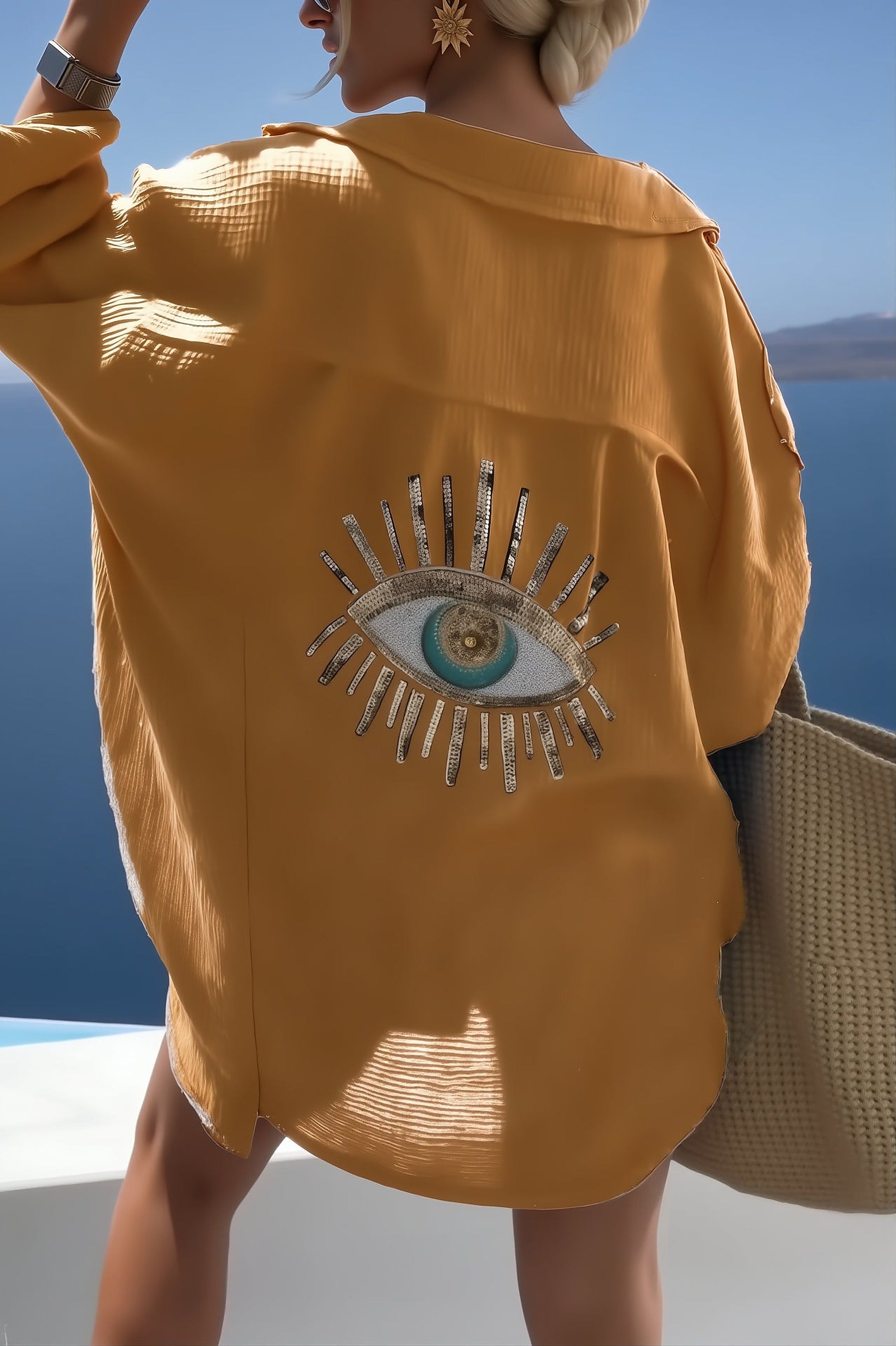 Woman wearing golden Costa Coral bikini with embellished eye motif, ocean backdrop visible, Scandinavian swimwear design.